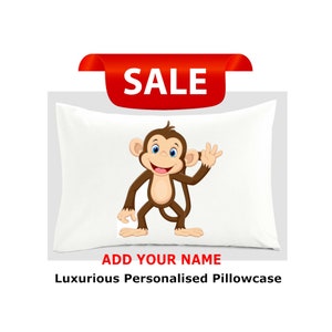 May include: White pillowcase featuring a cartoon monkey wearing a brown shirt and smiling. The pillowcase reads "ADD YOUR NAME" and "Luxurious Personalised Pillowcase".