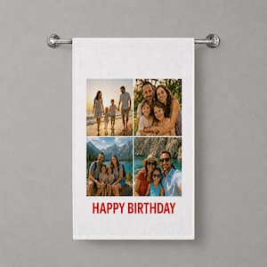 May include: A white rectangular towel hanging on a silver metal rail, featuring a four-panel photo collage of families in outdoor settings. The text HAPPY BIRTHDAY is printed in bold red capital letters at the bottom of the white fabric surface.