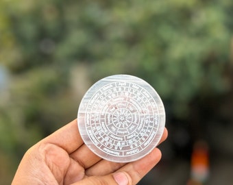 May include: A clear crystal disc with a circular design featuring the days of the week, months of the year, and the alphabet. The disc is engraved with the words "Yes" and "No" in the center.