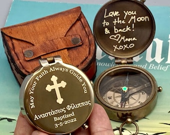 Puede incluir: Una brújula de latón con una funda de cuero. La cara de la brújula tiene una cruz dorada y la inscripción "May Your Faith Always Guide You" en inglés y griego. La inscripción también incluye el nombre "Αναστάσιος Φίλιππας" y la fecha "3-5-2022". La tapa de la brújula tiene un mensaje escrito a mano que dice "Love you to the Moon & back! Mama xoxo".