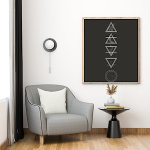 Peut inclure: Une illustration en noir et blanc de cinq formes géométriques, un triangle, un cercle et trois carrés, sur un fond noir avec un cadre en bois. L'illustration est accrochée à un mur blanc au-dessus d'un fauteuil gris et d'une table d'appoint noire avec un vase de fleurs séchées.