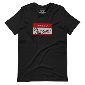 Puede incluir: Camiseta negra con una etiqueta de nombre roja y blanca que dice "HELLO I'M AWESOME!"