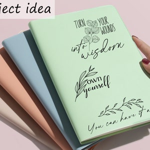 May include: A stack of four notebooks with different colored covers. The top notebook is light green and has the text "Turn your wounds into wisdom own yourself You can have it all" written on it in black.