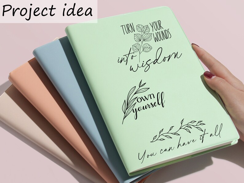 May include: A stack of four notebooks with different colored covers. The top notebook is light green and has the text "Turn your wounds into wisdom own yourself You can have it all" written on it in black.
