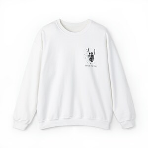 May include: White long-sleeve sweatshirt with a black skeleton hand making a rock and roll sign and the text "Ride or Die" printed on the front.