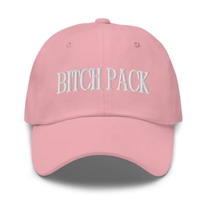 May include: A pink baseball cap with white embroidered text that reads "BITCH PACK".