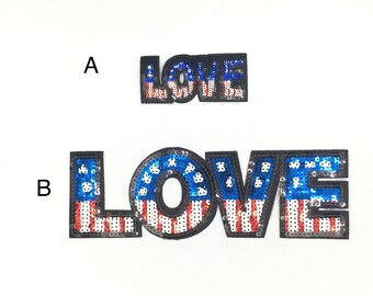 May include: Two iron-on patches with the word "LOVE" in large, bold letters. The letters are covered in sequins that are red, white, and blue, resembling the American flag. The smaller patch is labeled "A" and the larger patch is labeled "B".
