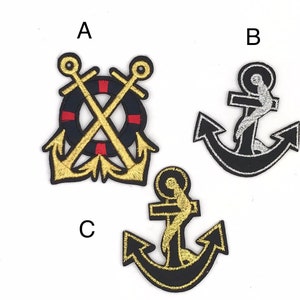 May include: Three embroidered iron-on patches with nautical themes. The first patch features two gold anchors crossed over a black and red life preserver. The second patch is a black anchor with a silver outline. The third patch is a black anchor with a gold outline.