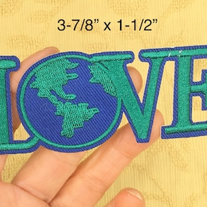May include: Green and blue embroidered iron-on patch with the word "LOVE" with a globe in place of the "O". The patch measures 3-7/8 inches by 1-1/2 inches.