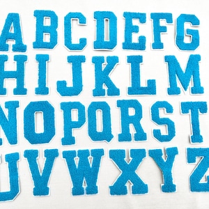 May include: A set of 26 blue felt letter patches, each letter of the alphabet is individually cut out and has a white outline. The letters are arranged in alphabetical order.