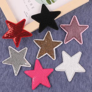 May include: Seven star-shaped iron-on patches in various colors, including red, pink, black, gold, silver, and white. The patches are made of sequins and are perfect for adding a touch of sparkle to clothing, bags, or other accessories.