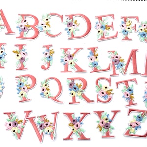 May include: A set of 26 pink felt alphabet letters with floral embroidery. Each letter is decorated with a cluster of colorful flowers.