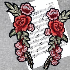 May include: Two embroidered floral patches with red, pink, and green flowers. The patches are on a white sheet of music with the text "Ludwig van Beethoven (1770-1827)".