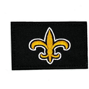 May include: A black embroidered patch with a gold fleur-de-lis design.