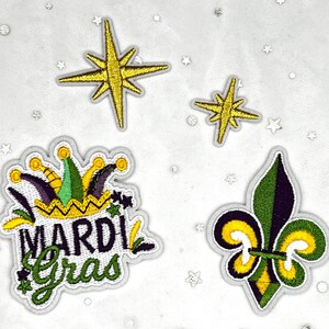 May include: Embroidered patches featuring Mardi Gras themes. Includes a patch with the words "Mardi Gras", a fleur-de-lis, and starburst designs in gold, green, purple, and yellow. These patches are ideal for decorating clothing or accessories.