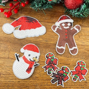 May include: A collection of Christmas-themed sequined patches, including a Santa hat, gingerbread man, snowman, and candy cane bows. The patches are red, white, and brown, with green accents. Perfect for holiday crafts and decorations.