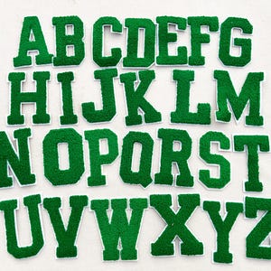 May include: Green felt letter patches for crafting projects. The letters are in uppercase and range from A to Z.