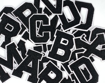May include: A pile of black felt letter patches with white outlines. The letters include A, B, C, D, M, P, and R.