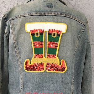 May include: A red and green sequined elf boot patch with a yellow border. The patch is 6 inches by 7 inches and is iron-on.
