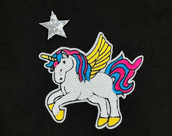 May include: A white unicorn with a pink and blue mane and tail, yellow wings, and a gold horn. The unicorn is standing on a black background with a silver star.