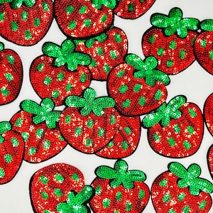 May include: A collection of red and green sequined strawberry patches. The strawberries are all different sizes and shapes, and they have a shiny, sparkly finish.