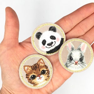 May include: Three embroidered patches featuring a panda, a rabbit, and a cat. Each patch is circular and has a beige background with a yellow border.