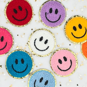 May include: Nine embroidered smiley face patches with gold trim. The patches are in various colors including red, purple, white, yellow, orange, blue, and pink.
