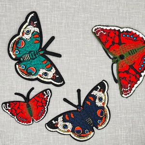 May include: Four embroidered butterfly patches in various colors, including red, green, black, and white. The butterflies are all different sizes and have intricate details.
