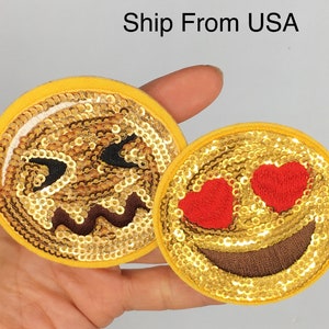 May include: Two gold sequin iron-on patches with embroidered smiley faces. One face has red hearts for eyes and the other has a mischievous expression.