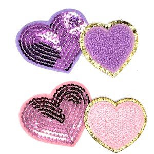 May include: Two pairs of heart-shaped fabric patches. One pair is purple with sequins and a gold outline. The other pair is pink with sequins and a gold outline.