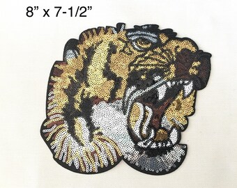 May include: A large, detailed, embroidered iron-on patch of a tiger's face with a fierce expression. The tiger is made of gold, silver, and black sequins. The patch measures 8 inches by 7-1/2 inches.