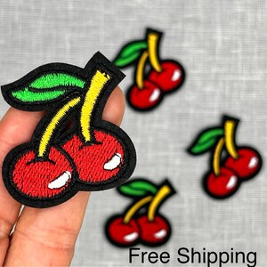 May include: Four embroidered iron-on patches of red cherries with green leaves. The cherries are yellow and red.