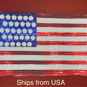 May include: A red, white, and blue American flag made of sequins. The flag is a patch or iron-on.