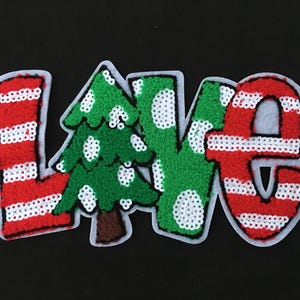 May include: A festive patch spelling "LOVE" with red and white striped letters and a green Christmas tree. The letters and tree are outlined in white and embellished with sequins, set against a black background.