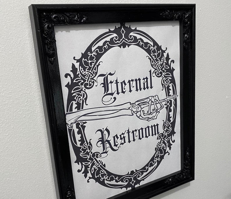 May include: Black and white framed sign with an ornate design. The sign reads "Eternal Restroom" with a skeletal hand pointing to the right.