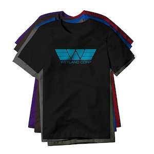 May include: Black t-shirt with a teal graphic of a stylized "W" and the text "WEYLAND CORP". The shirt is stacked with other t-shirts in various colors, including gray, purple, blue, and red.
