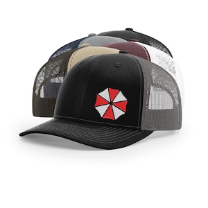 May include: A collection of baseball caps in various colors, including black, gray, and navy. Each cap features a mesh back and a front emblem with a red, white, and black design. The caps are arranged in a row, showcasing their different color options.