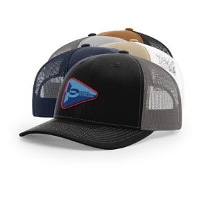 May include: A collection of trucker hats in various colors, including black, navy, and tan. Each hat features a mesh back and a curved brim. The front of the black hat displays a blue and red patch with the text "Benthic Petroleum".