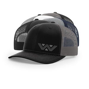 May include: A stack of baseball caps in various colors, including black, gray, white, and navy blue. Each cap has a mesh back and a curved brim. The front of the black cap features a tonal embroidered "W" logo.