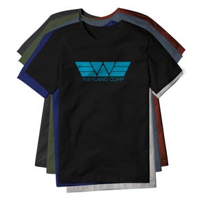 May include: A black short-sleeve t-shirt featuring a blue graphic logo of a stylized letter W with wings and the text WEYLAND CORP printed underneath. The shirt is layered over a stack of other t-shirts in various colors including olive, blue, and red.