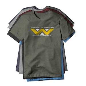 May include: Several short-sleeved t-shirts in various colors, including gray, blue, and maroon, are stacked. The front shirt is olive green with the text "WEYLAND-YUTANI CORP" and "BUILDING BETTER WORLDS" in white and yellow.