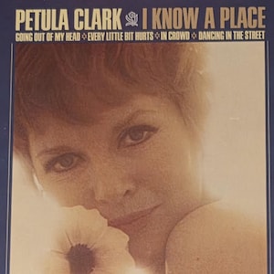 Peut inclure: Pochette d'album vinyle vintage de Petula Clark, intitulé "I Know a Place". La couverture présente une image sépia de Petula Clark et une bordure bleue. Les titres des chansons incluent "Going Out of My Head" et "Dancing in the Street".
