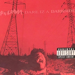 Op de afbeelding: Een rode cd-hoes met de tekst "REDMAN DARE IZ A DARKSIDE". De illustratie toont elektriciteitsmasten en een schreeuwend gezicht. Een sticker met waarschuwing voor ouders is zichtbaar.