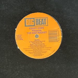 May include: A black vinyl record album cover with the text "STREET WISE" in red, arched along the top and bottom edges. The album title is "THE MAD RACKET" by Kenny Dope, with a circular orange label in the center.