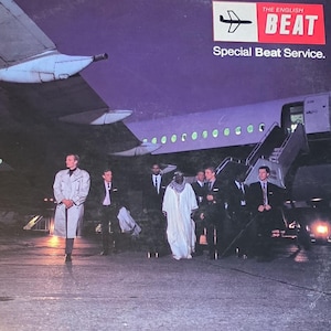 May include: Album cover for "The English Beat" featuring a group of people standing on an airport tarmac in front of a plane. The album title and band name are in red and white text. The album is titled "Special Beat Service."