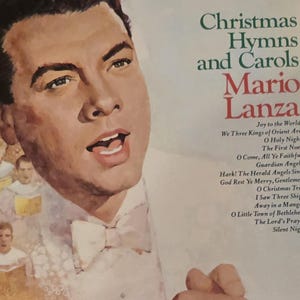 Pode incluir: Capa de álbum de vinil vintage com Mario Lanza, intitulada "Christmas Hymns and Carols". A capa apresenta um retrato pintado de Lanza, com títulos de músicas em verde e vermelho. O logotipo da RCA Camden é visível.