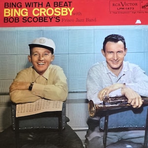 May include: Vintage vinyl record album cover for "Bing With A Beat" by Bing Crosby with Bob Scobey's Frisco Jazz Band. The cover features two men, one holding a trumpet, and the album title in red and yellow.