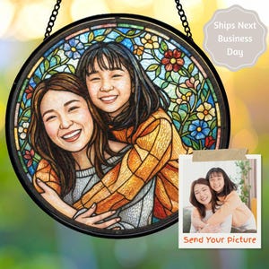 May include: Round stained glass art piece featuring a portrait of two smiling people, surrounded by a floral border. The artwork is framed in black and hangs from a chain. A small photo with the text "Send Your picture" is also included.