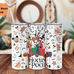 Puede incluir: Un vaso blanco con un tema de Halloween con Mickey Mouse, Donald Duck y Goofy vestidos de brujas. El vaso est&aacute; decorado con varios iconos de Halloween, incluyendo calabazas, murci&eacute;lagos, fantasmas y estrellas. El texto "It's Just A Bunch Of Hocus Pocus" est&aacute; impreso en el vaso.