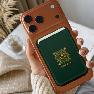 May include: A tan phone case with a dark green cardholder. The cardholder displays a QR code and the Instagram handle @VALENTINYUS. The case is held in a person's hand.